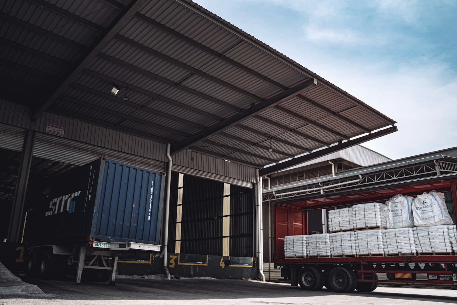 Two trucks docked at a warehouse loading bay
