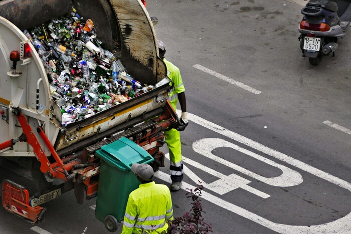 Workers collecting trash into a garbage truck